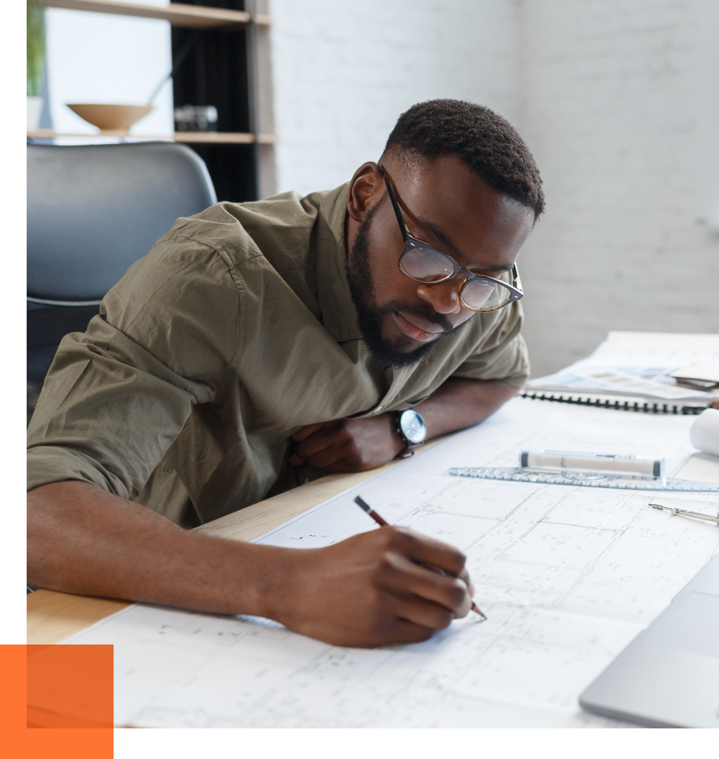 Male engineer writing on blueprints