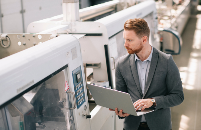 manufacuting engineer with laptop - Search Solution Group male manufacturing engineer in suit walking cnc shop with laptop