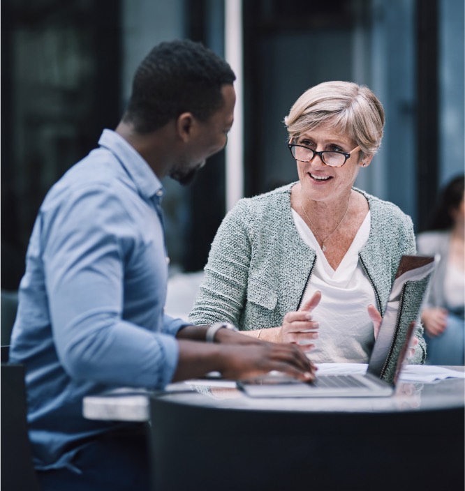 total rewards recruitment professional looking up from his laptop to a client sitting at the table with him